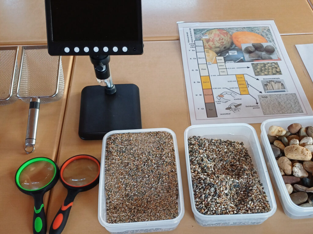 Lehrmaterial auf einem Tisch: Siebe, Lupen, USB-Microskop, Gesteins- und Bodenartenproben