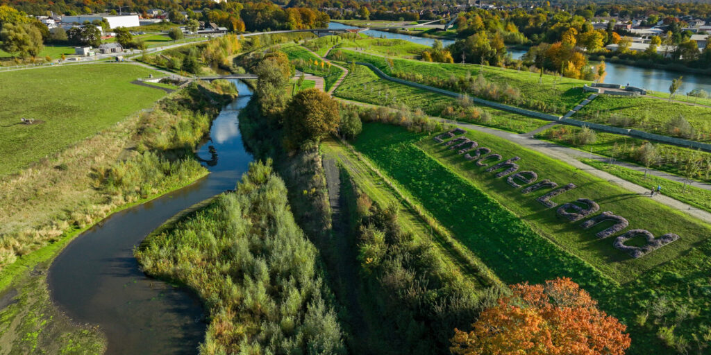 18.10.2025, Castrop-Rauxel, Herbst im Emscherland, Blick flussaufwärts auf die Emscher mit Emscherstrand. Hinten rechts die neue Brücke „Sprung über die Emscher“